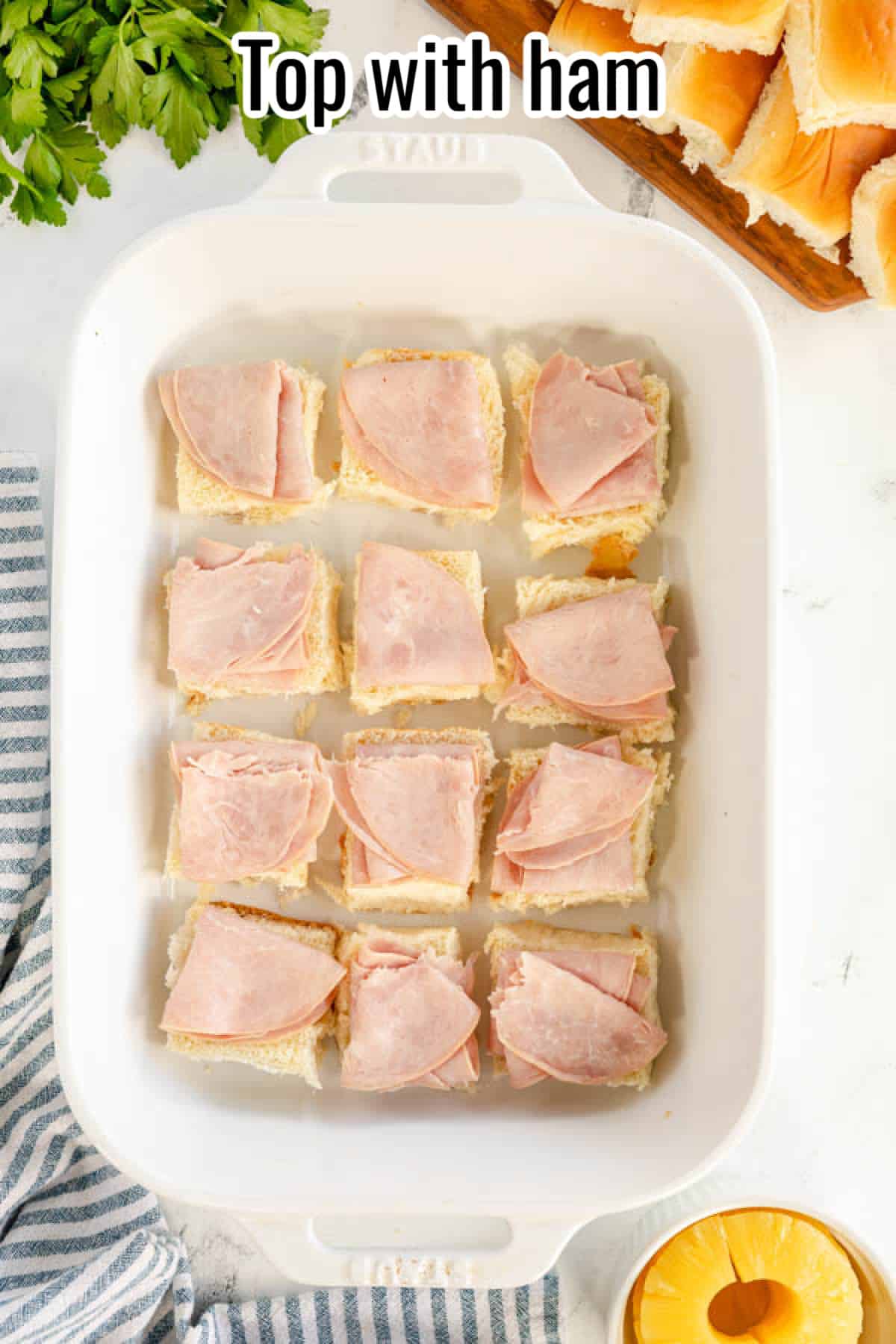 Top ham and cheese sliders in a white baking dish.