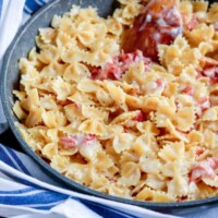 ham and cheese pasta with a wooden spoon in a skillet