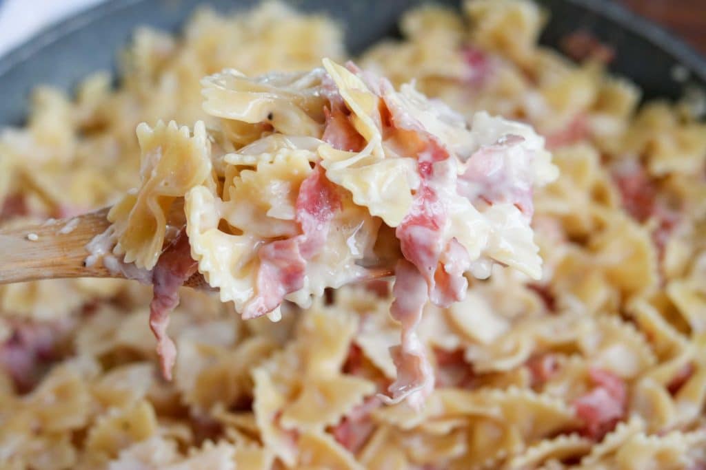  ham and cheese pasta with a wooden spoon in a skillet