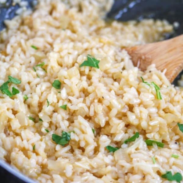 risotto in a skillet with a wooden spoon, and parsley