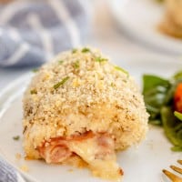Chicken cordon bleu with salad on a white plate.