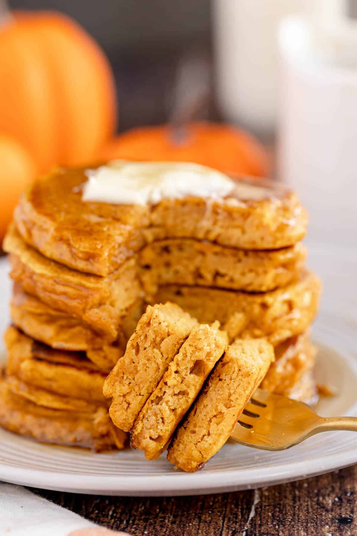 pumpkin spice pancakes in a stack with a fork full of cut pancakes.