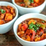 Three bowls of slow cooker vegetarian chili on a wooden table.