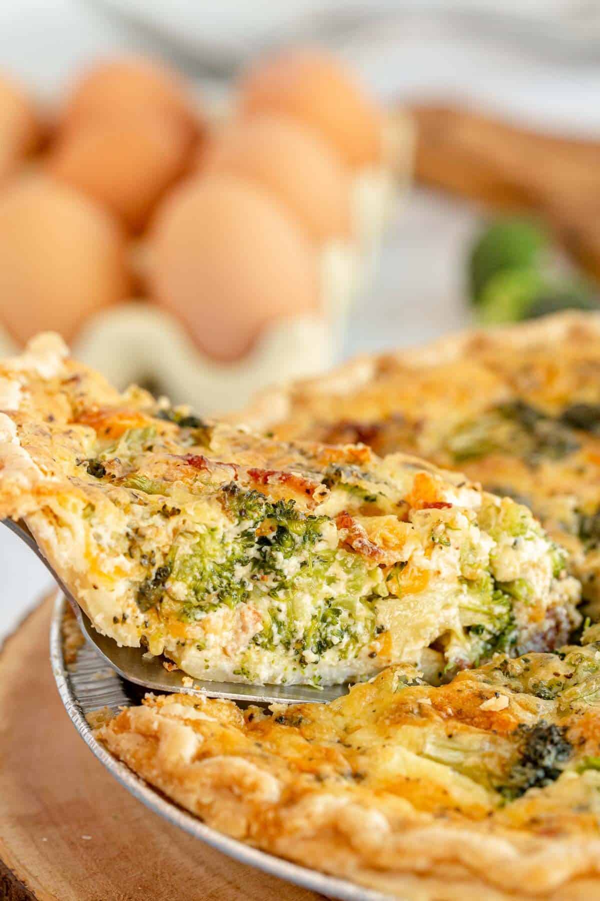 broccoli quiche being lifted out of a pie pan