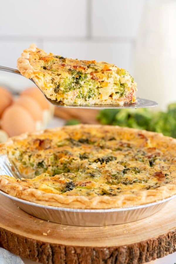 broccoli quiche being lifted out of a pie pan