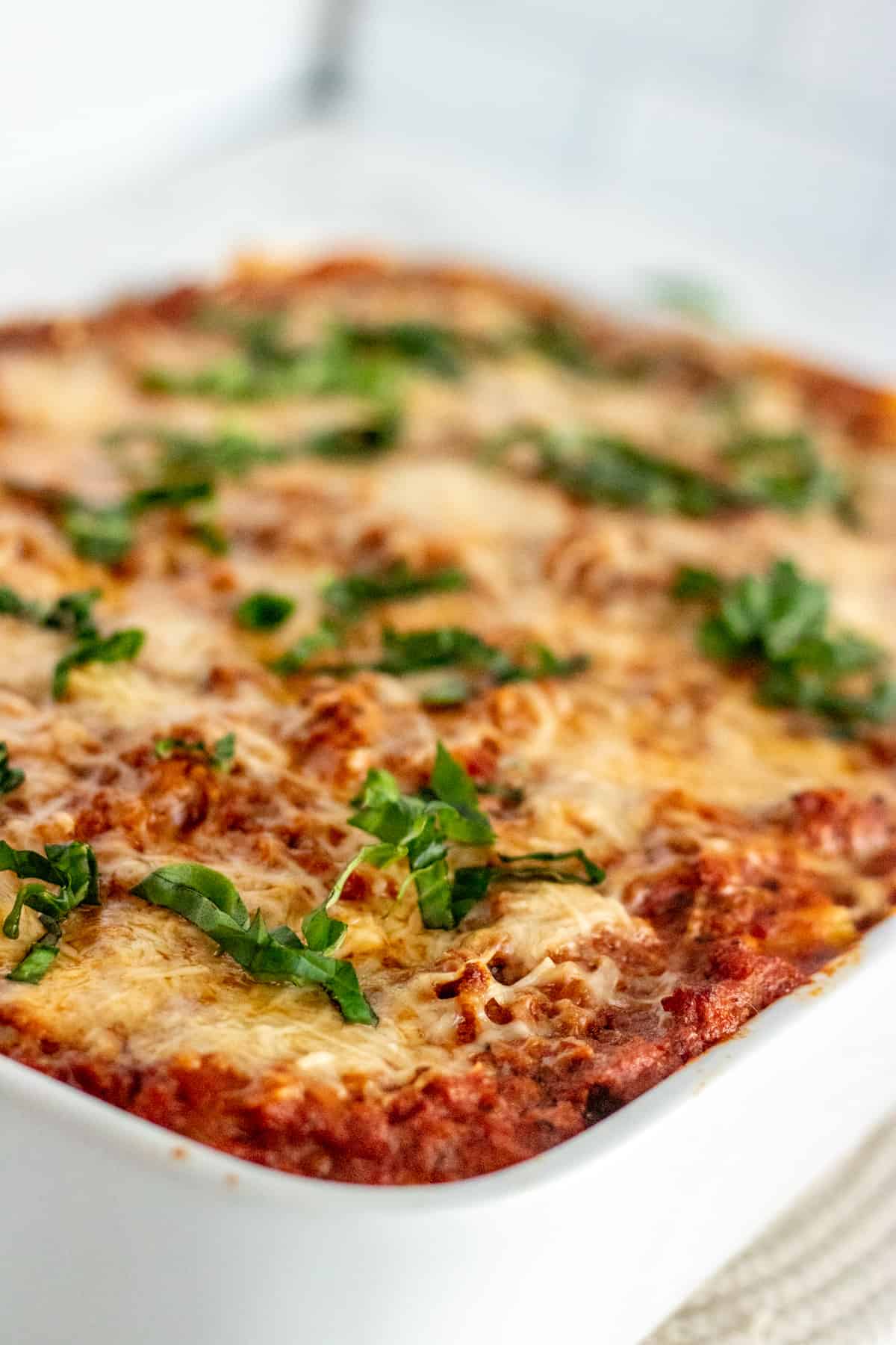 Baked ziti in a white baking dish with parsley over the top