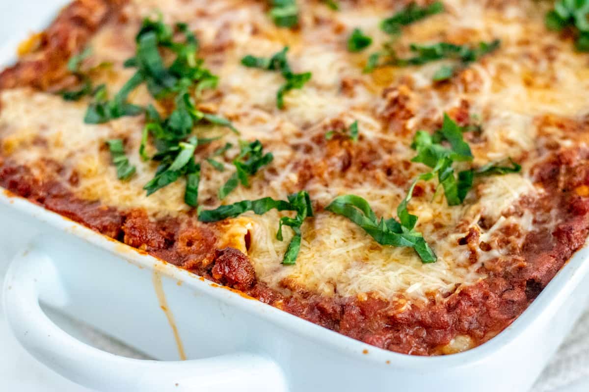 Baked ziti in a white baking dish with parsley over the top