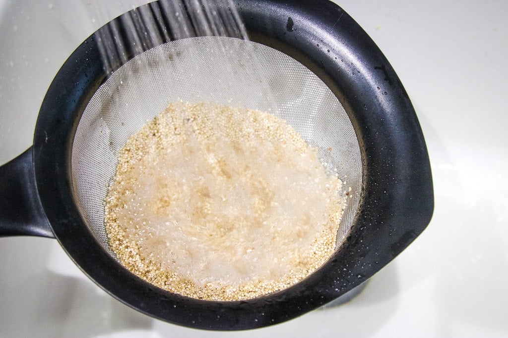 rinsing uncooked quinoa in a mesh colander