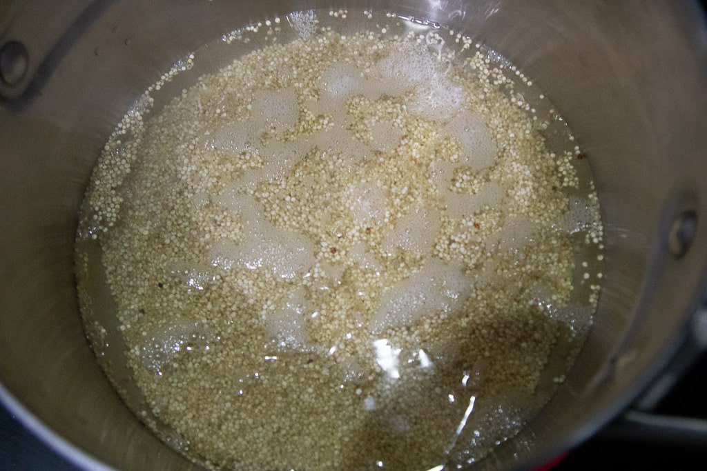 uncooked quinoa in saucepan, bubbles forming