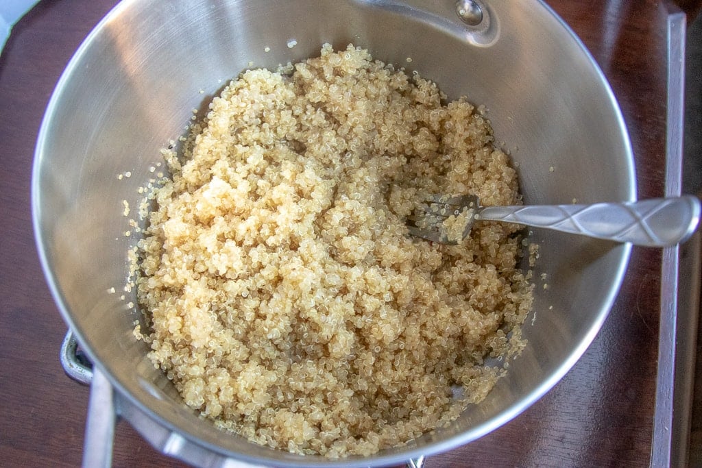 cooked quinoa in a saucepan with a fork to fluff