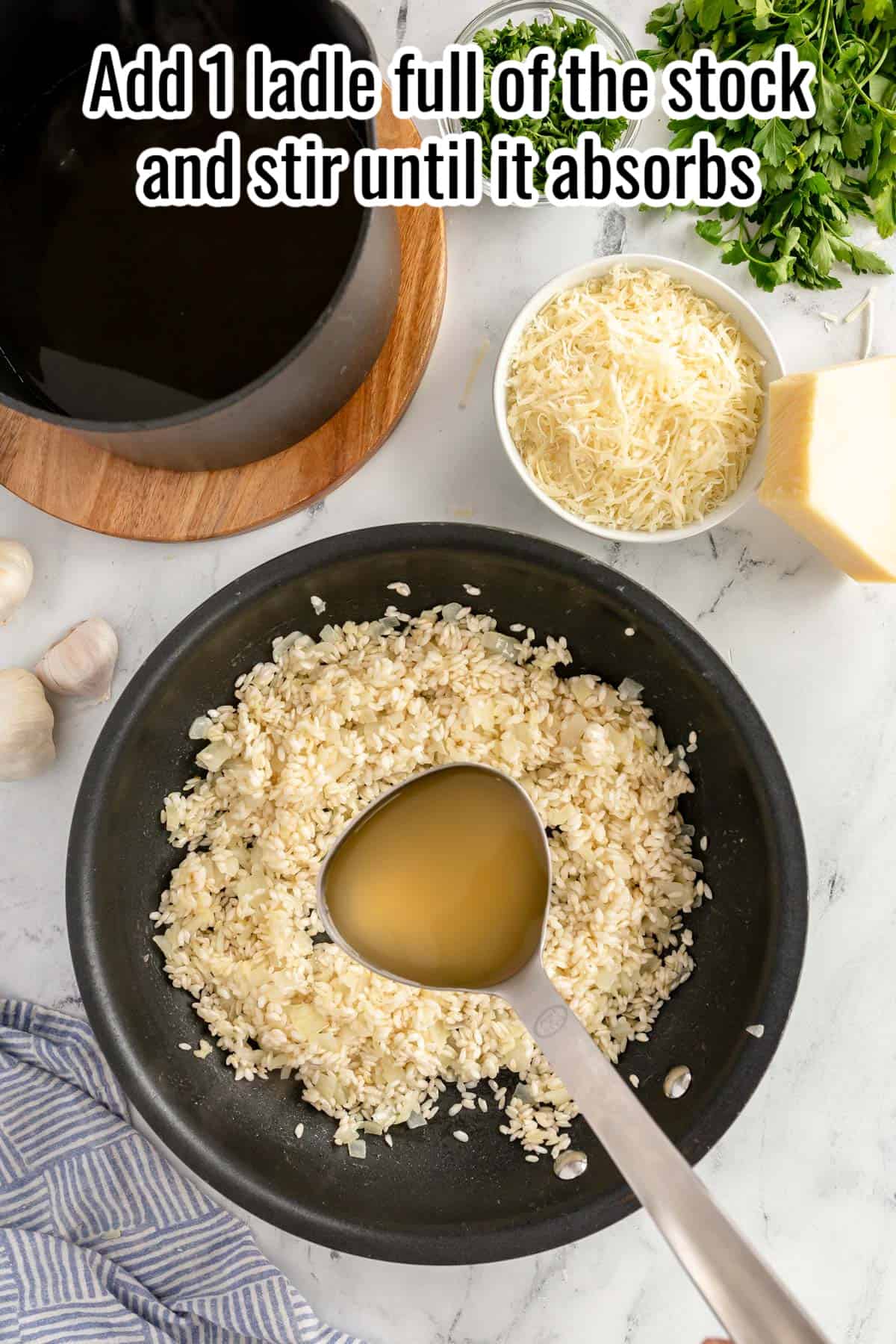a black skillet of risotto with a ladle full of stock.