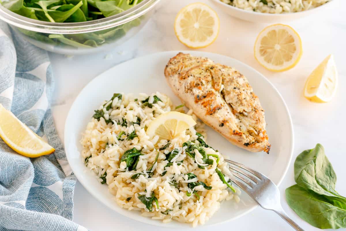 spinach risotto with lemon on a white plate with chicken