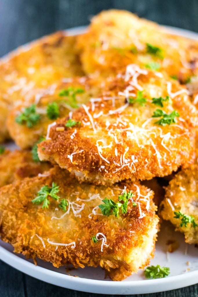 Pork schnitzel on a white plate with parsley and parmesan