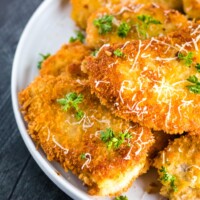 pork schnitzel on a white plate with parmesan and parsley