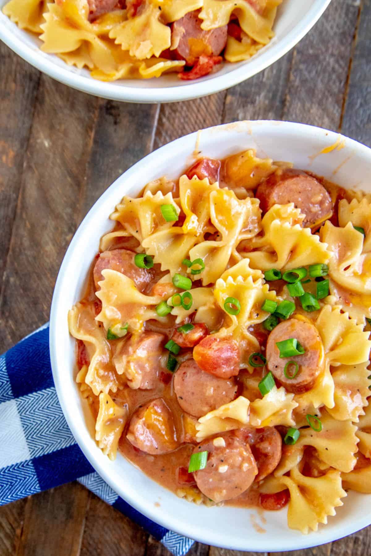 bowl of sausage pasta with a checkered napkin.