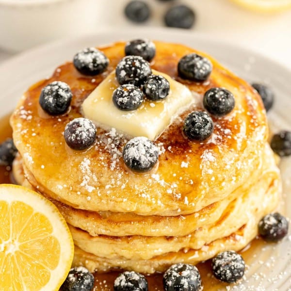 stack of pancakes with a cut lemon and blueberries.