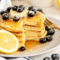 stack of pancakes with a cut lemon, ricotta and blueberries.