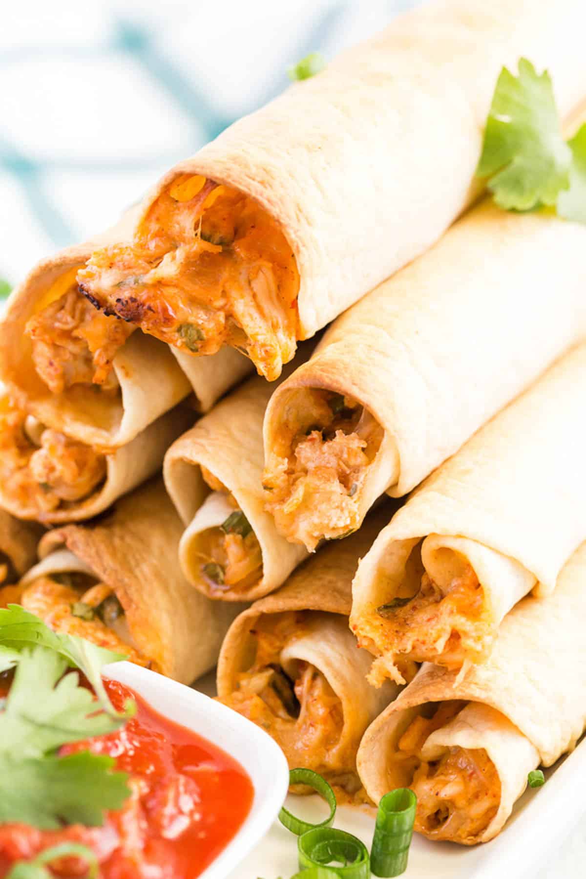 chicken taquitos in a stack with salsa.