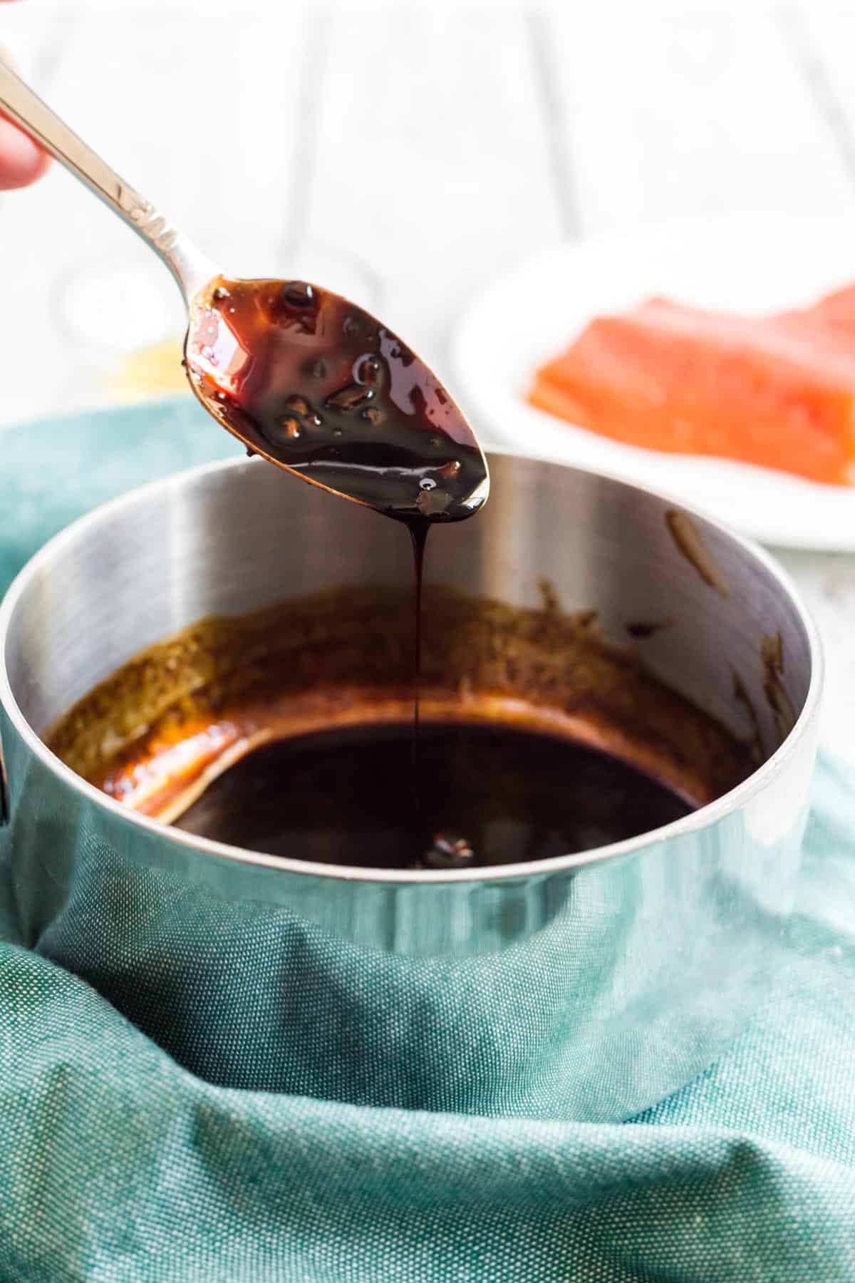 a spoon showing balsamic glaze in a cup