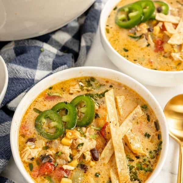 Bowls of chicken tortilla soup with tortilla chips and jalapenos and limes.