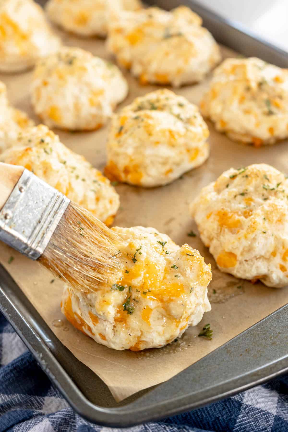 cheddar bay biscuits being brushed with garlic butter.