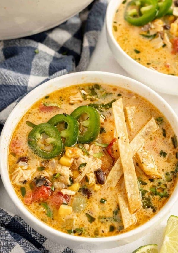 Bowls of chicken tortilla soup with tortilla chips and jalapenos and limes.