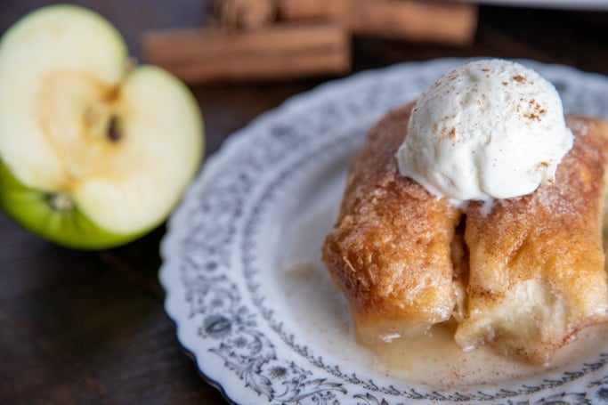 apple dumplings on a white plate with a scoop of icecream