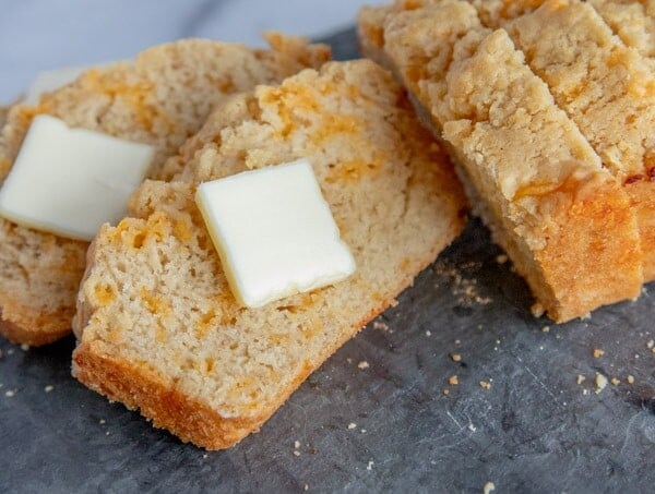 cheddar beer bread slices on a slate board, with butter