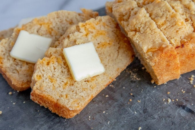 cheddar beer bread slices on a slate board, with butter