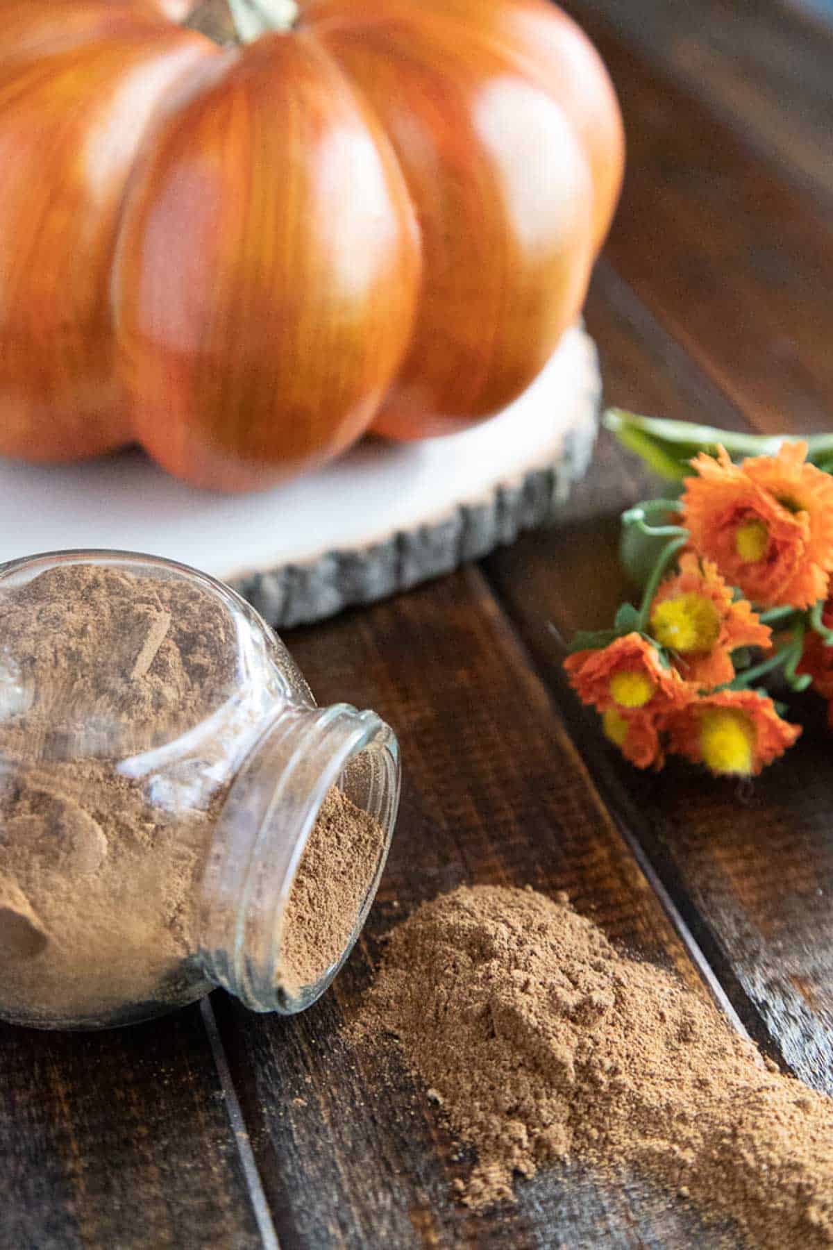 pumpkin pie spice spilling out of a glass jar on a wooden board