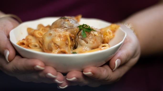 meatball casserole in a white bowl being held in hands