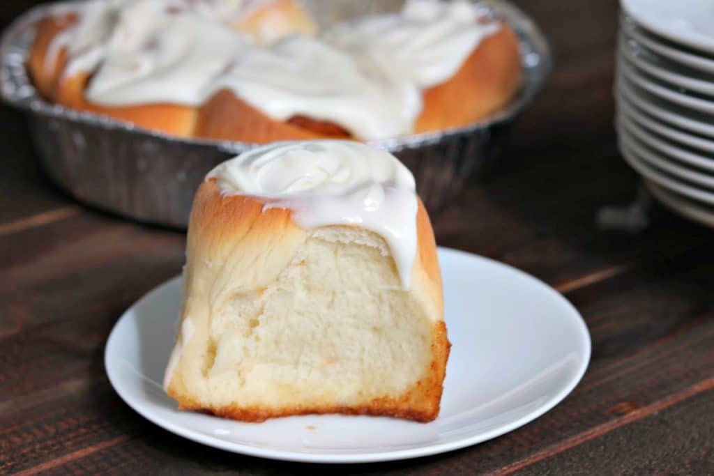 cinnamon roll with frosting on a white plate