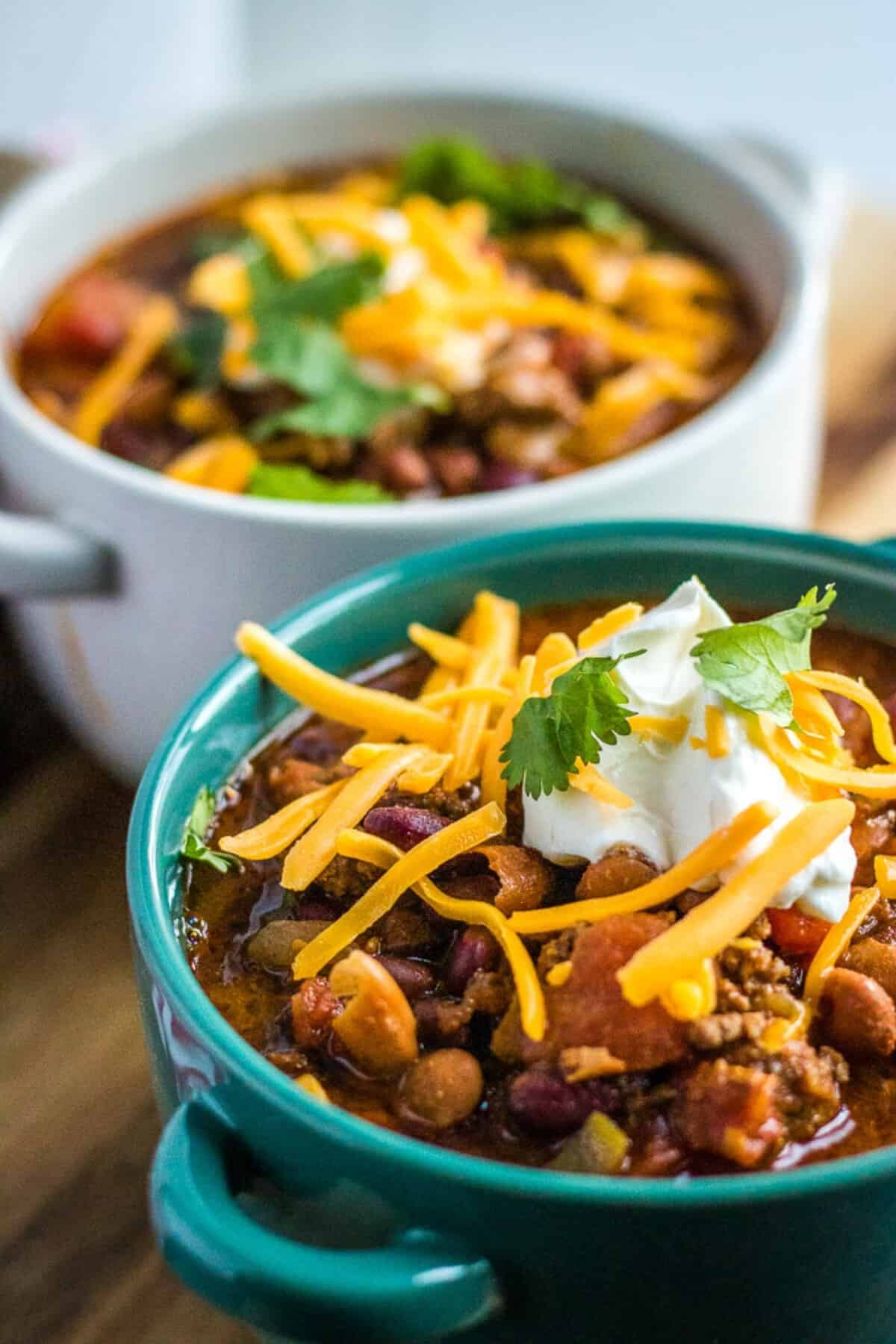 crockpot chili in a teal bowl with a spoon