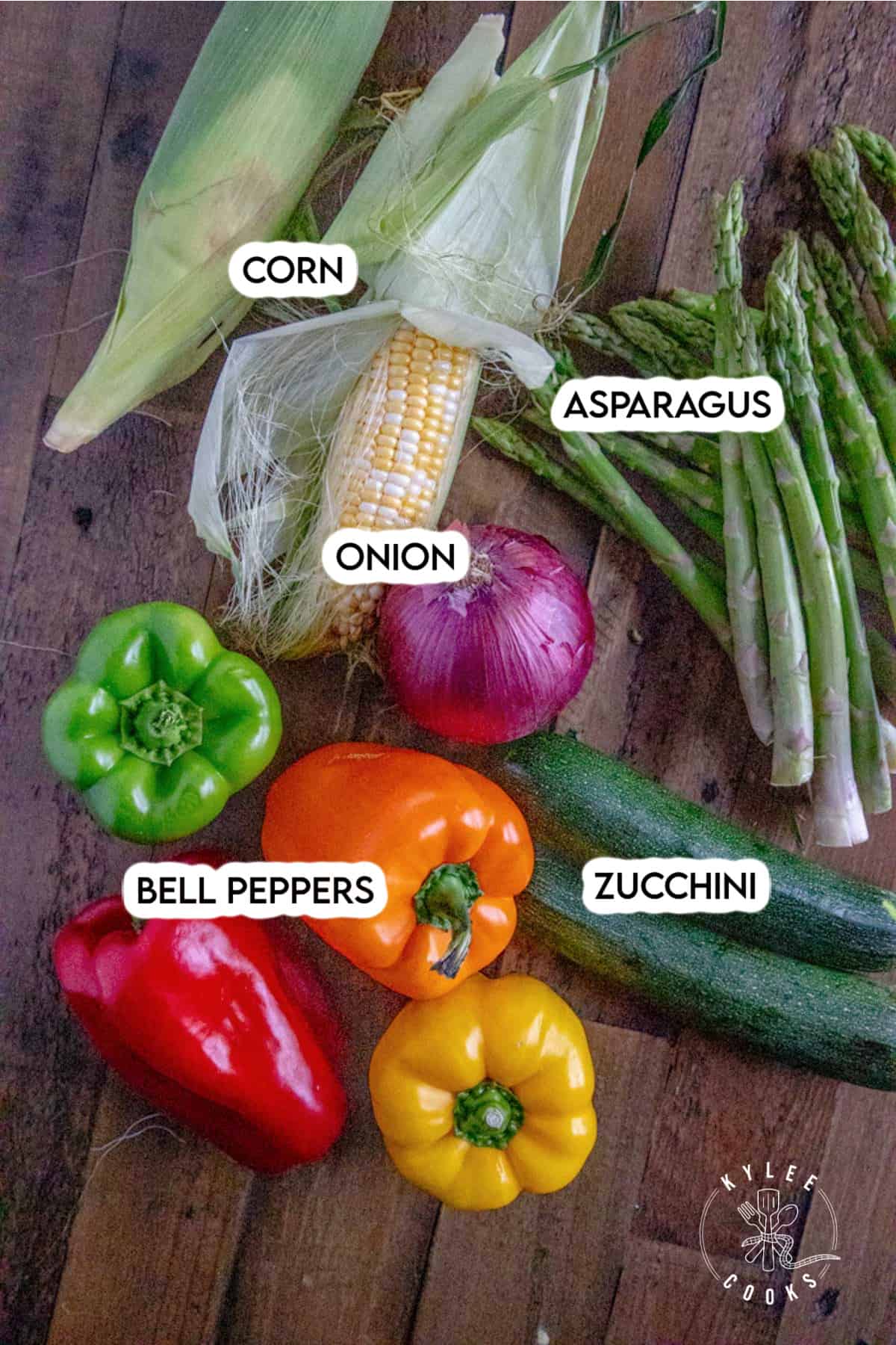 ingredients to make grilled veggies laid out on a wooden board and labeled.