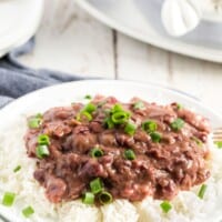 red beans and rice on a white plate with blue napkin, and green onions