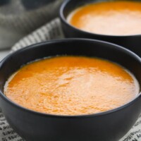 Roasted red pepper soup in black bowls, on newspaper