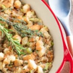 homemade stuffing in a red casserole dish with fresh herbs