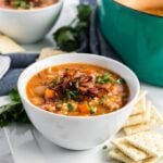 lentil soup in a white bowl with crackers