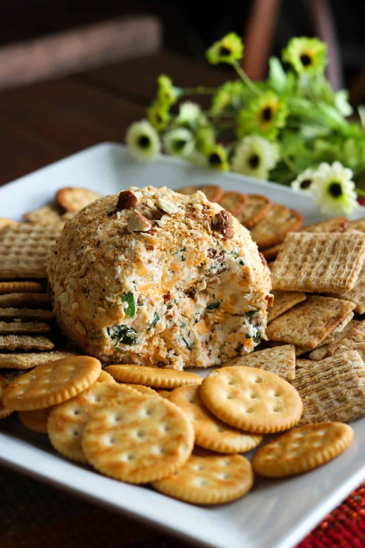 jalapeno popper cheeseball on a white plate with crackers.