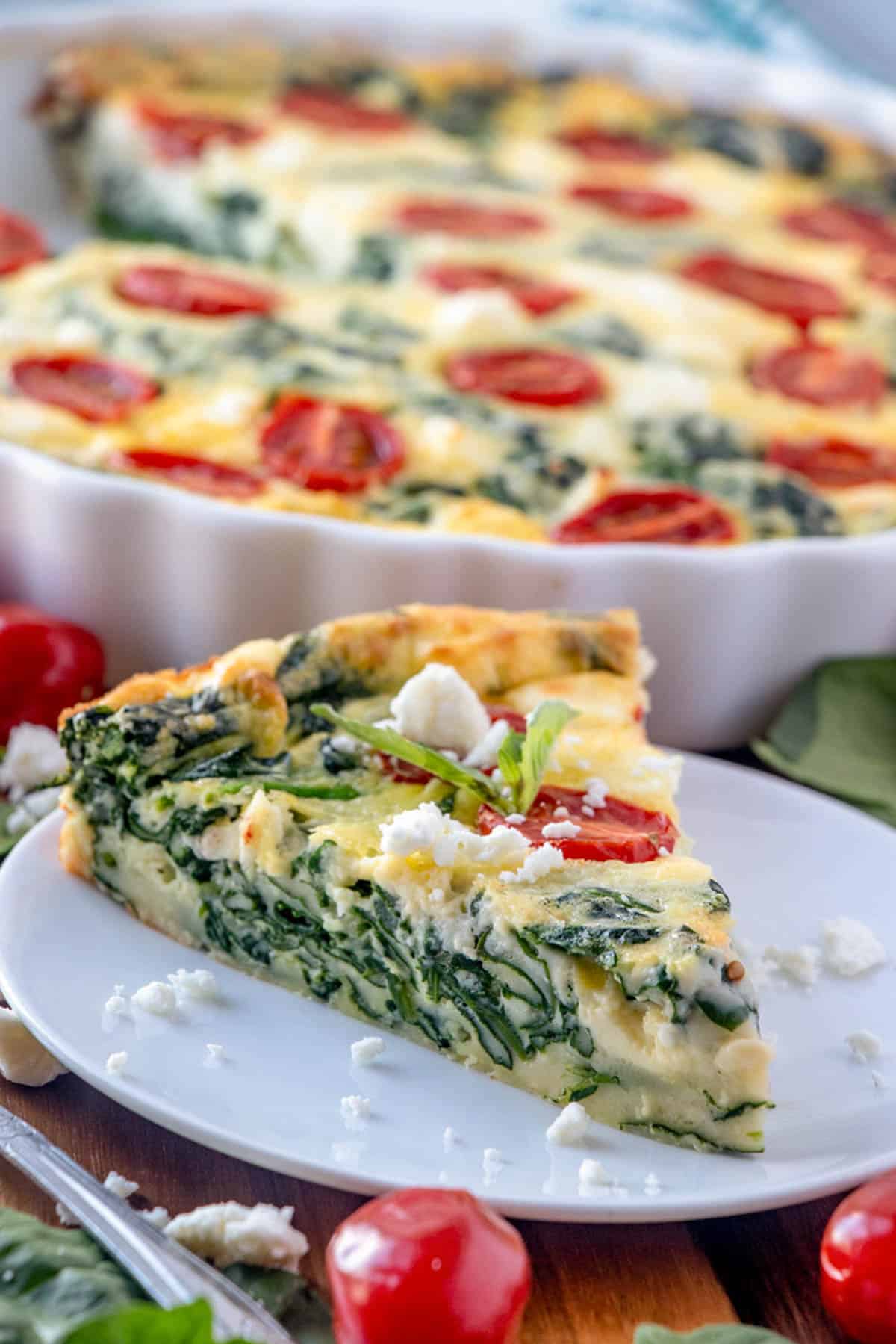 slice of spinach quiche on a white plate.