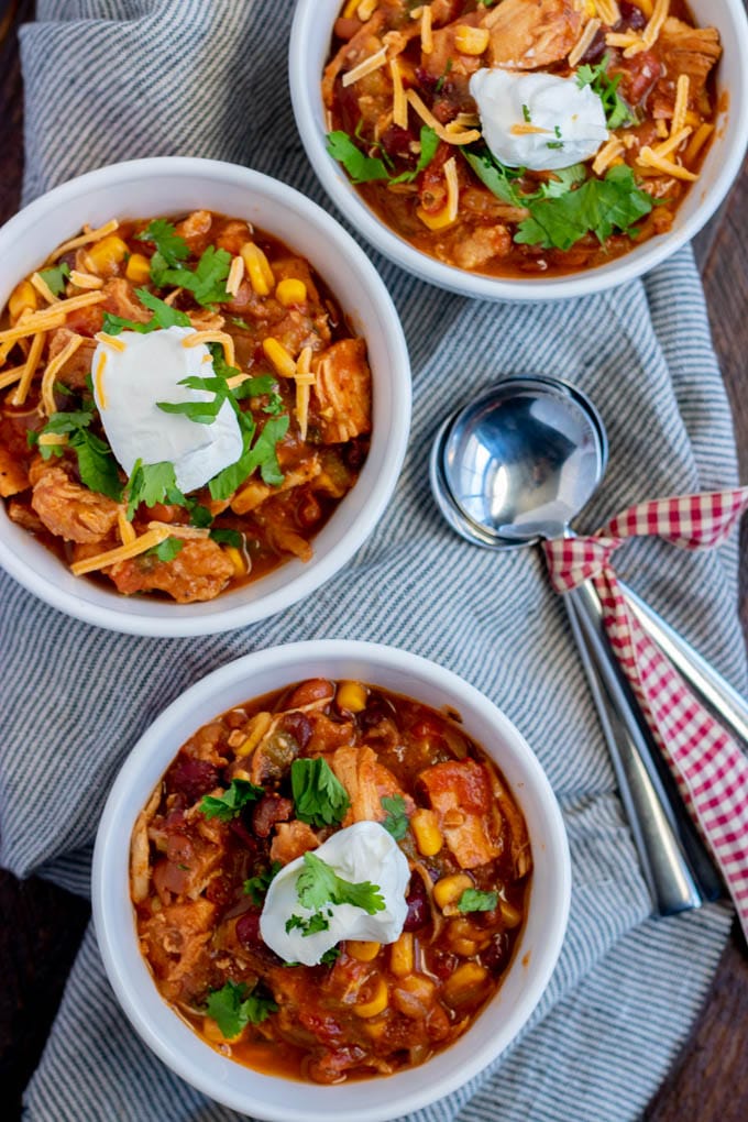 three bowls of chicken chili with spoons