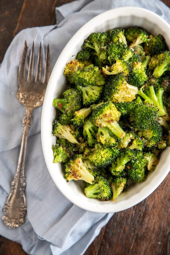 oven roasted broccoli in a white bowl with an antique fork