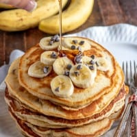 banana pancakes with syrup being poured over