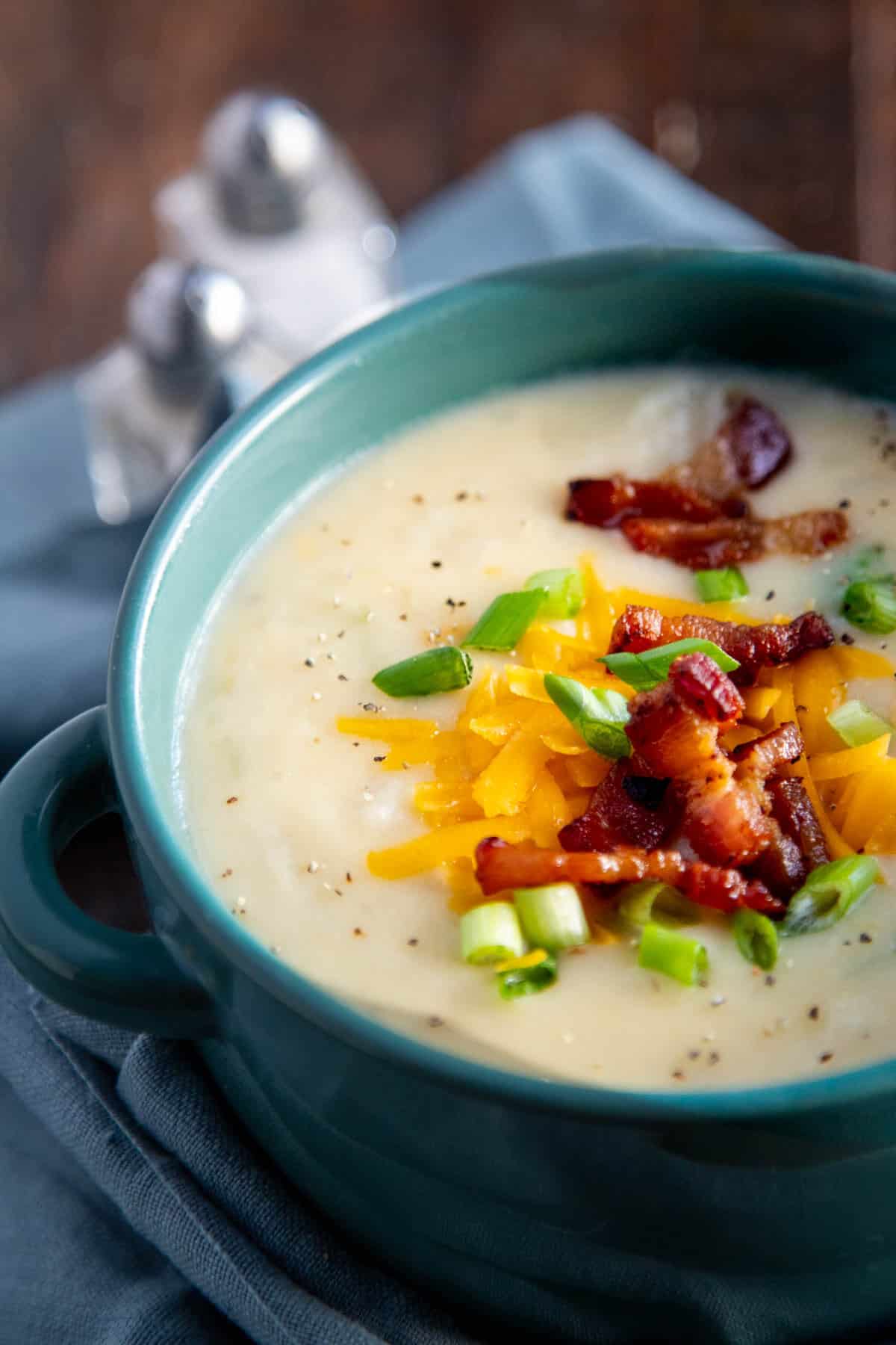 loaded baked potato soup in a teal bowl