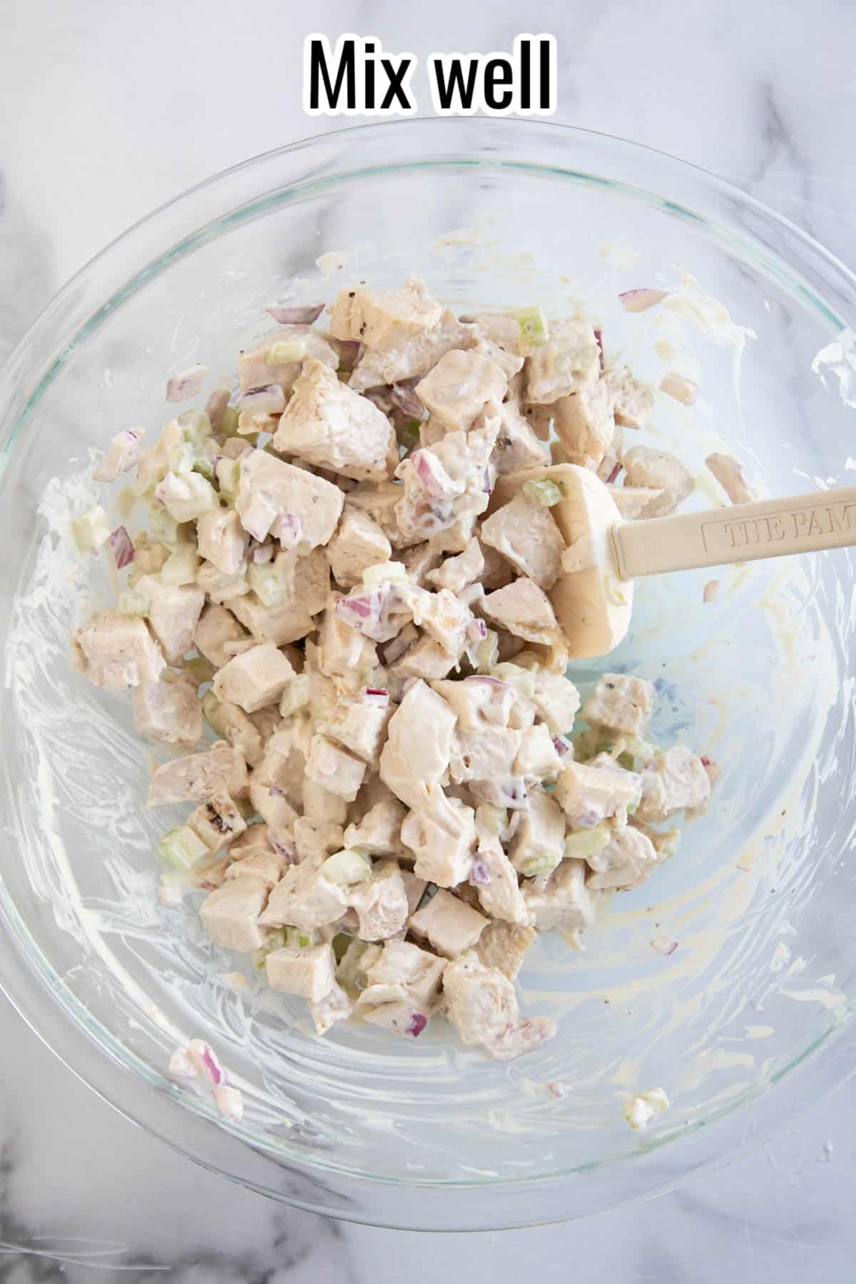 a glass bowl with mixed up chicken salad in it.