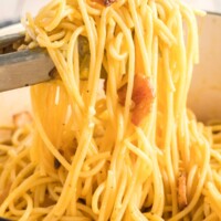 spaghetti carbonara being mixed with tongs