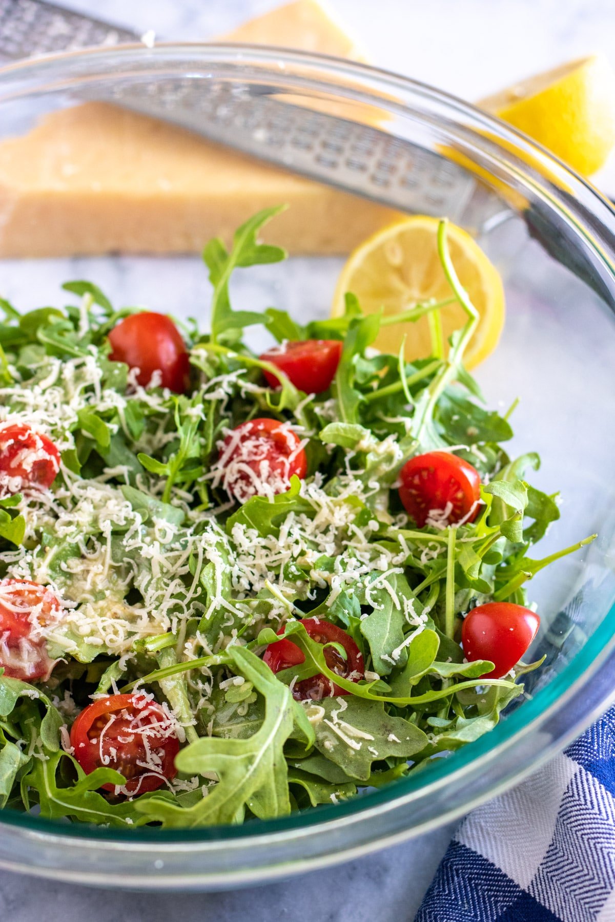 arugula salad in a bowl with lemon on the side
