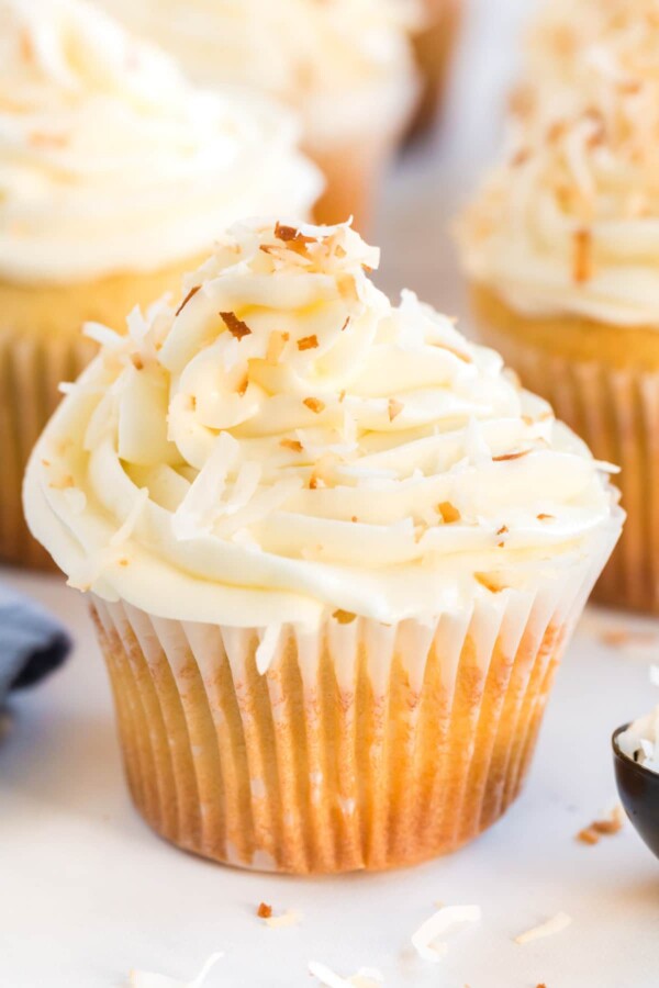 close up of a coconut cupcake with frosting and toasted coconut on top