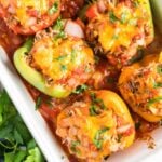 stuffed peppers in a white baking dish with parsley scattered