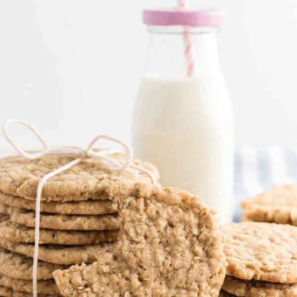 oatmeal cookies tied up with twine, with a bottle of milk in the background and a pink striped straw